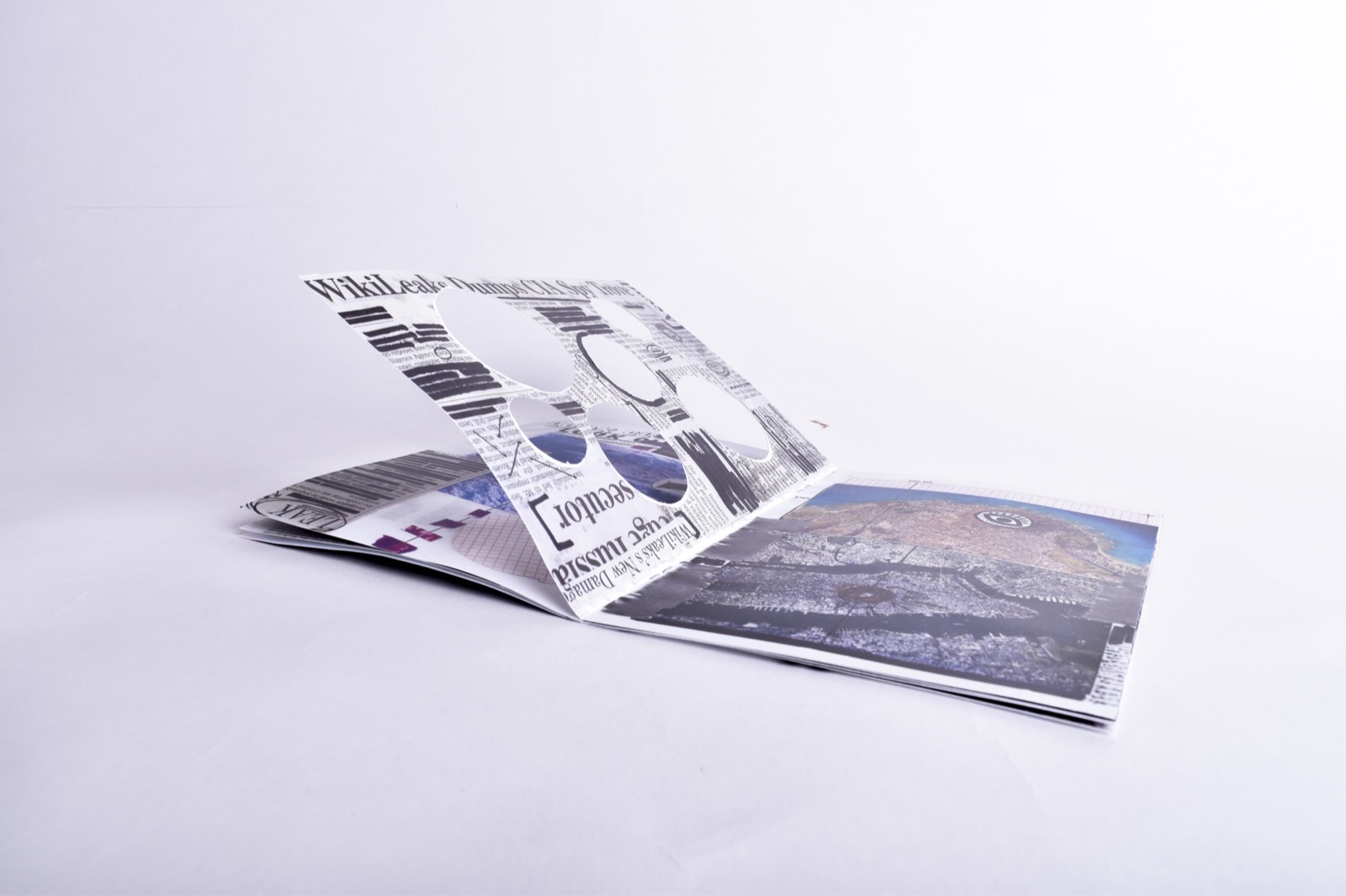 All Eyes On Us — zine tented open showing WikiLeaks die-cut page